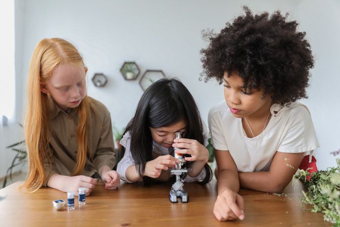 Children doing a science experiment and looking into a microscope